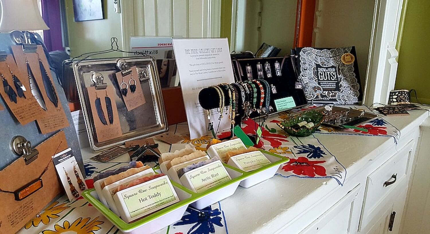 Table of wares for sale including soaps, jewelry and books.