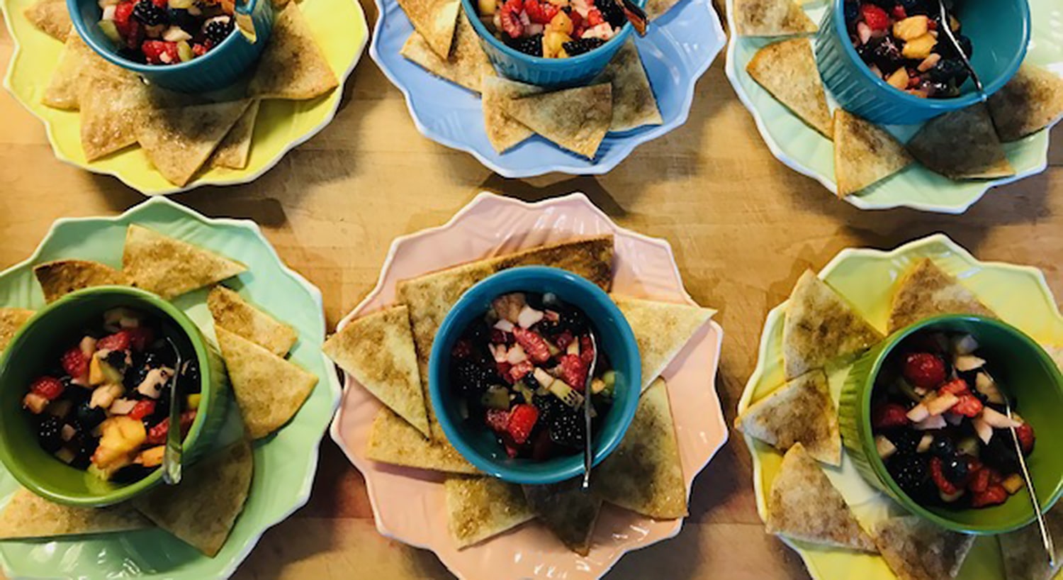 Colorful decorative dishes with mixed fruit salad and triangular flat bread.