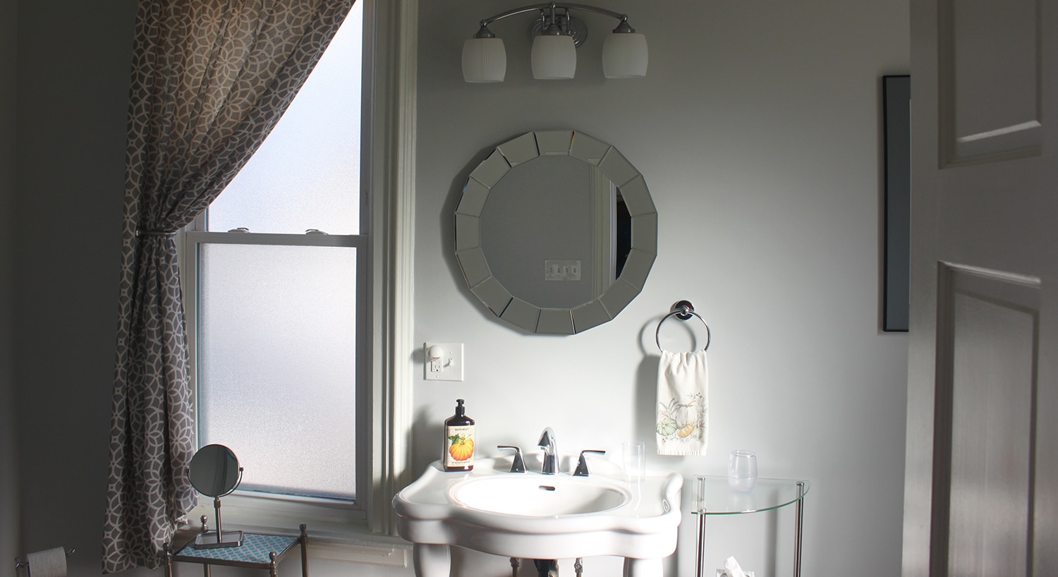 Large window, round mirror, and antique sink in the large bathroom in Julia's Room.