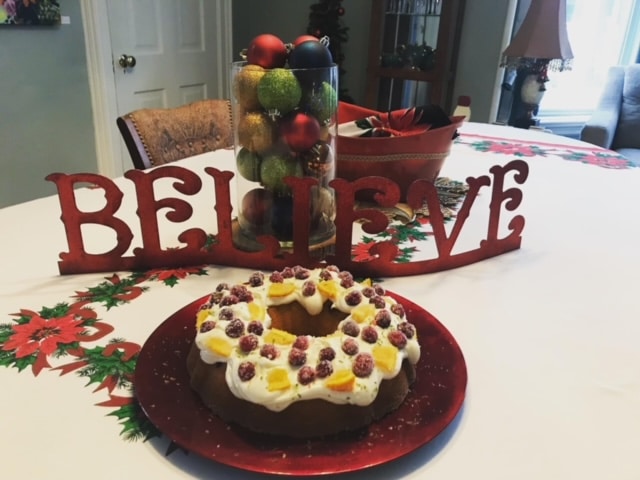 Photo of dining table with a cake and sign that reads "Believe"