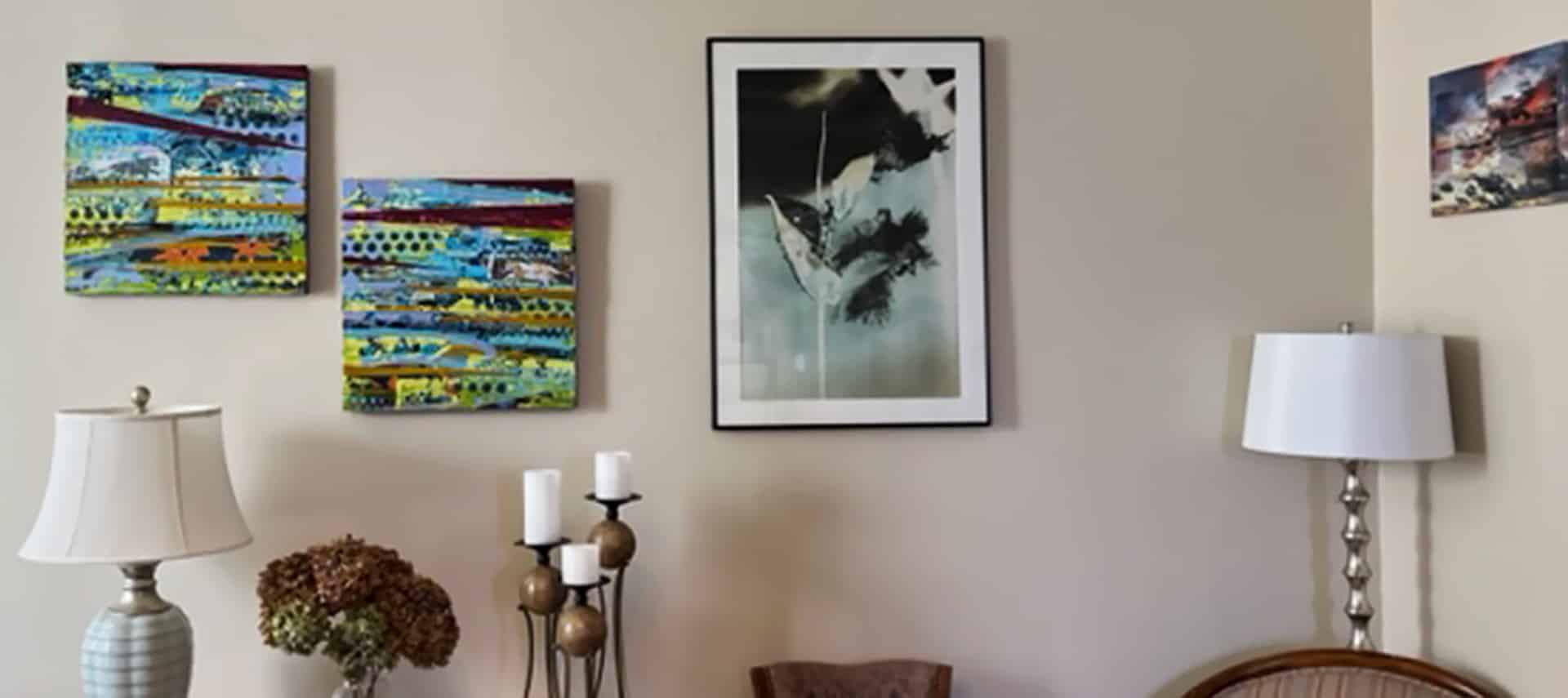 Three paintings and one photograph on tan walls.