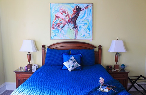 Guestroom with orange and blue walls with a queen bed and two nightstands with lamps.