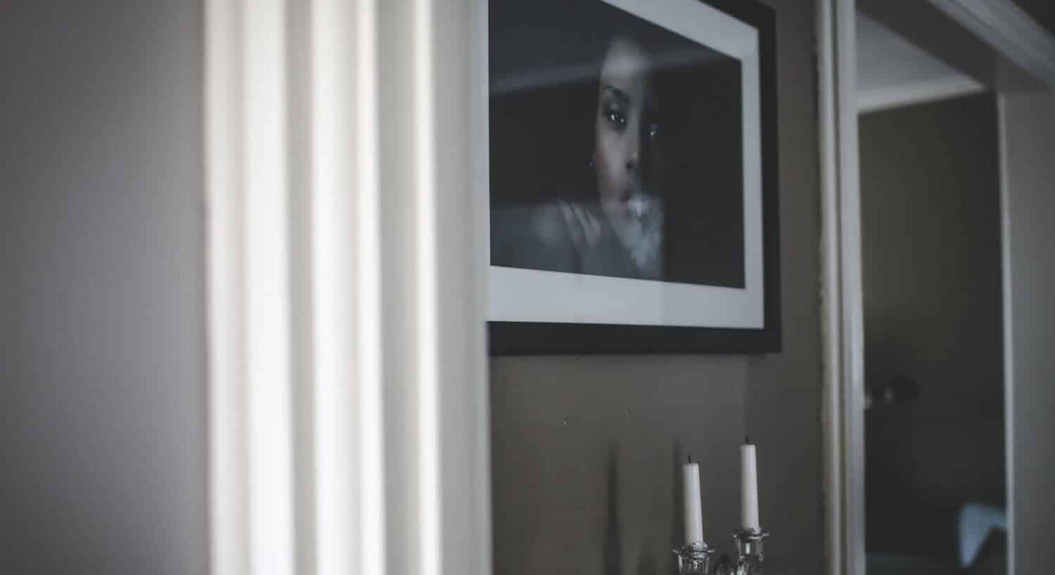 Black and white artistic photo of a photo of a woman over a table with candles.