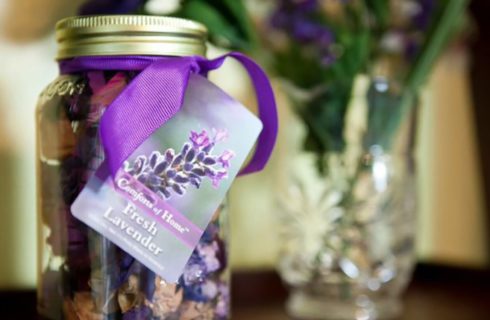 Mason jar full of fresh lavender popourri next to a vase with flowers.