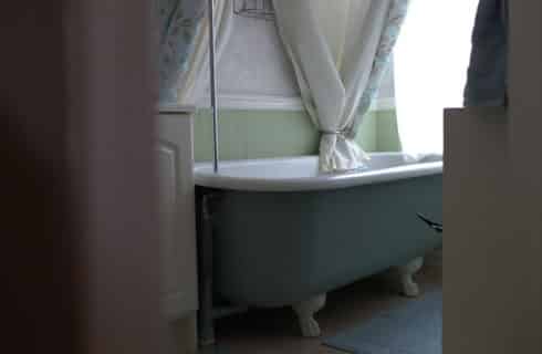 Blue clawfoot tub in a bathroom with a pitched roof.