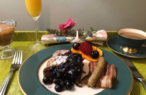 French toast with blueberry compote accompanied by sausage and bacon with coffee and orange juice.