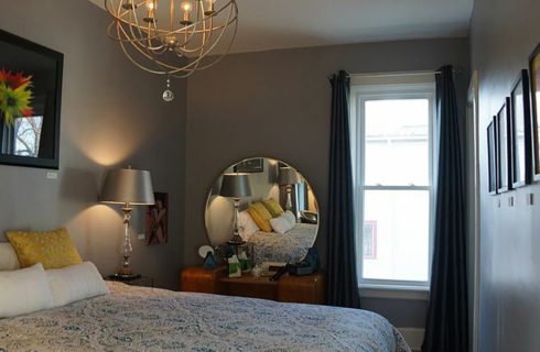 Bedroomw ith a queen bed, antique vanity and interesting light fixture.