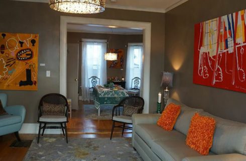 Large roomw ith beige walls and white trim holds a sofa and three chairs.