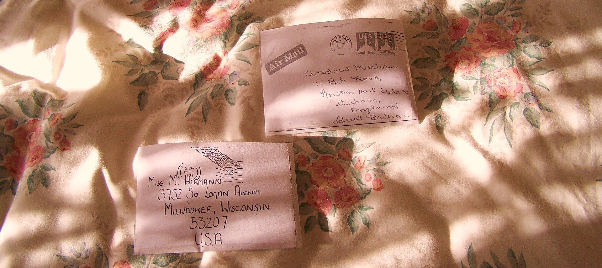 Two old letters with handwritten addresses on a cream and flowered blanket