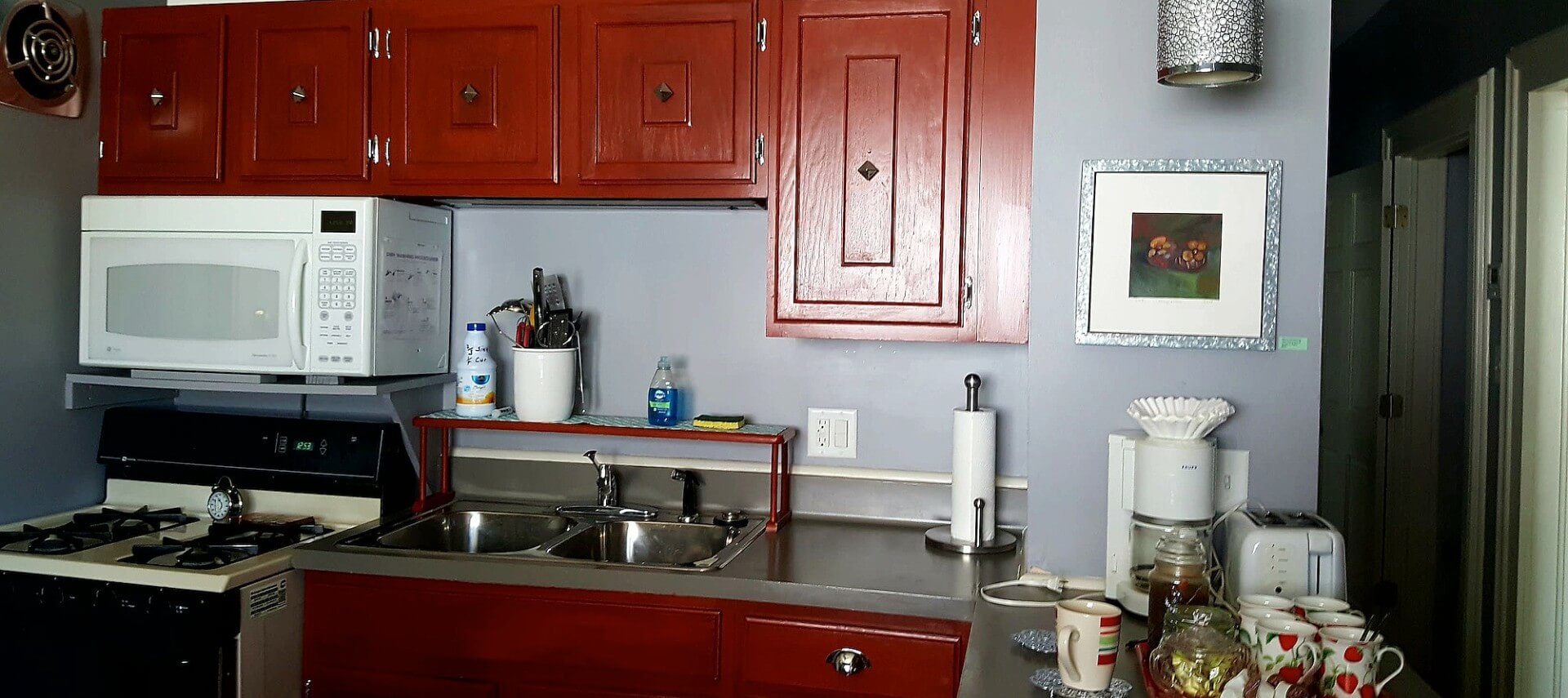 Kitchen with cherry cabinets, a gas stove and microwave and coffee station on the bar.