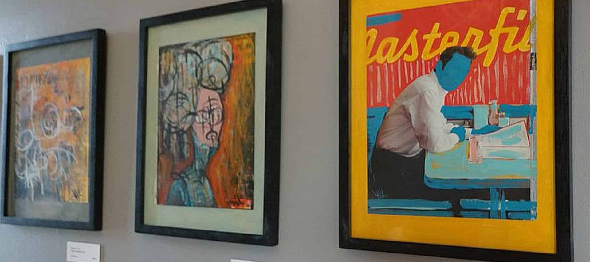 Series of art drawings and paintings along a wall.