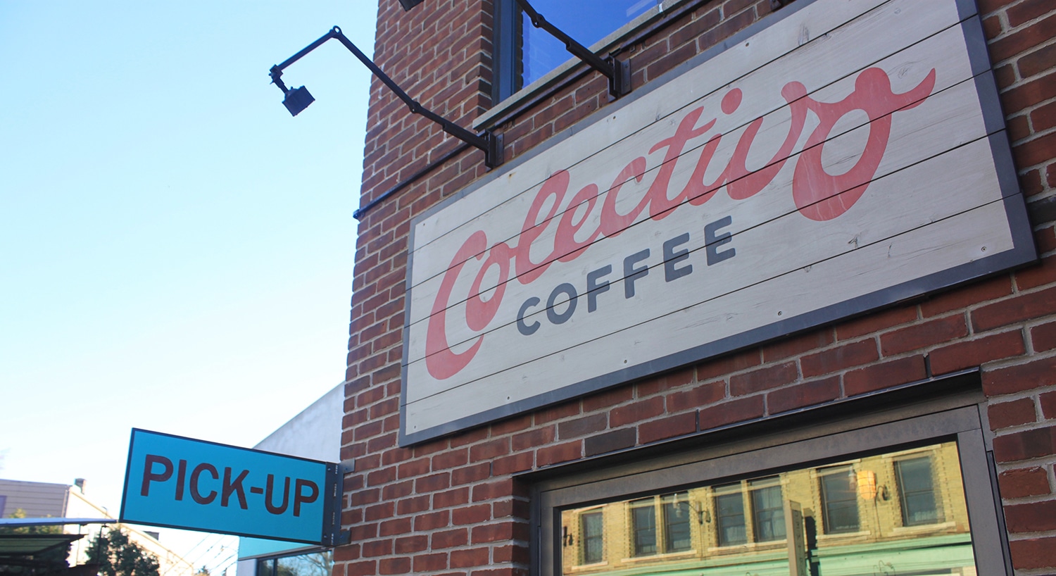 Colectivo Coffee sign painted on brick building, with Pick Up sign.