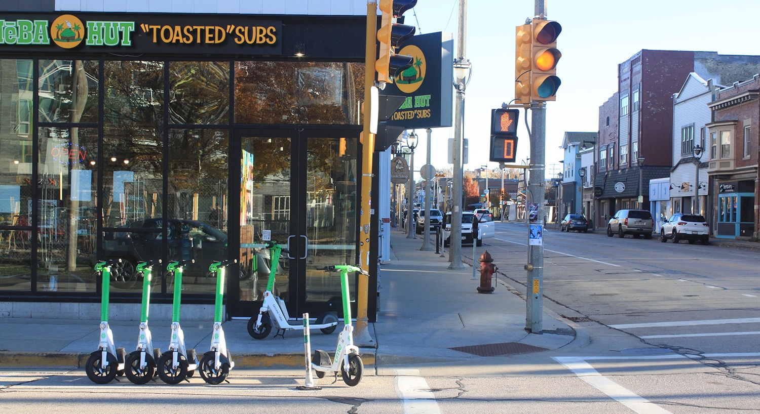 A row of rental scooters in front of Cheba Hut Toasted Subs restaurant